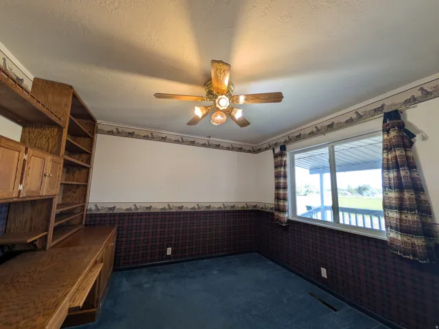 Built-in wood-finish cabinetry, built-in wood-finish shelving, overhead ceiling fan, and window