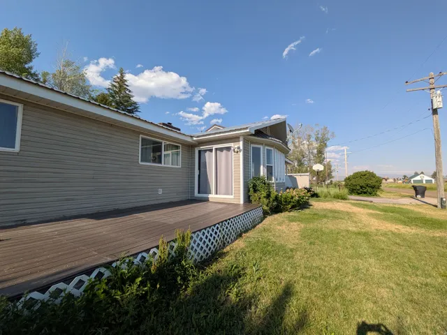 Exterior featuring neutral-toned siding, a spacious composite deck, multiple windows, and a curved window bay