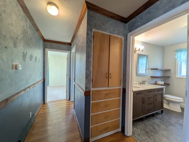 Hallway with wood-finish flooring and built-in storage cabinetry