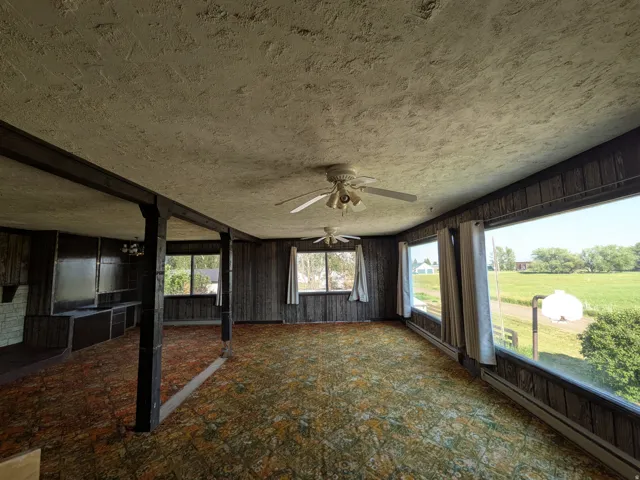 Room with wood-panel walls, patterned carpet, and multiple ceiling fans