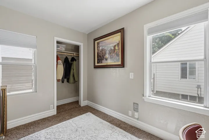 Bedroom #2 Neutral wall color with white trim, two windows, and a closet with a built-in shelf