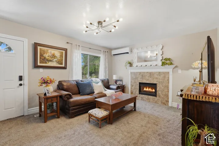Living area featuring a textured carpet, a built-in fireplace with tile surround and mantel, a modern ceiling light fixture, and an air conditioning unit