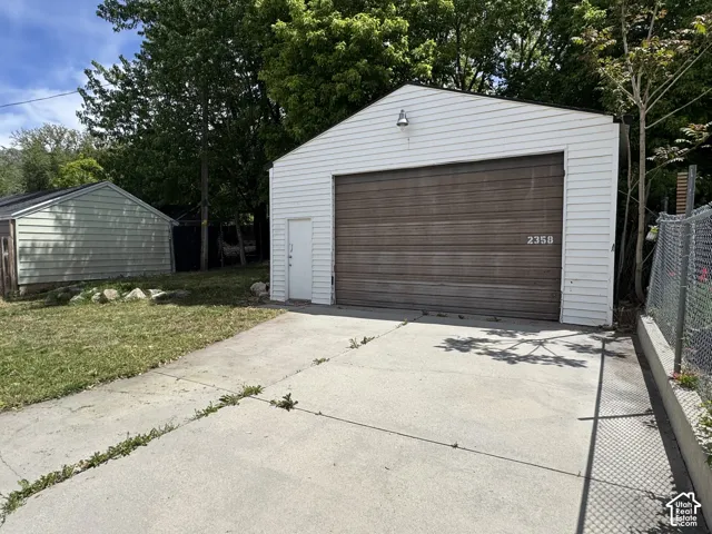 Detached garage with white siding and a wood-finish garage door