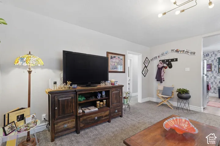 Recessed lighting in ceiling, neutral wall paint, warm gray carpet, and wood-finish entertainment console