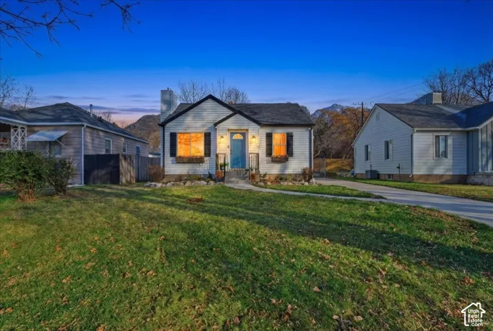 White siding exterior with black shutters, a blue front door, and a front yard with a green lawn