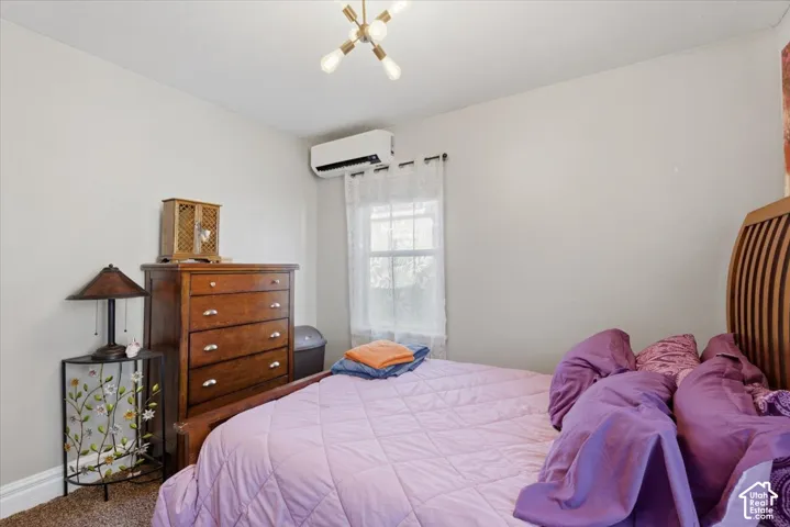 Bedroom #1 Modern ceiling light fixture, wall-mounted air conditioning unit, and a window with white sheer curtains