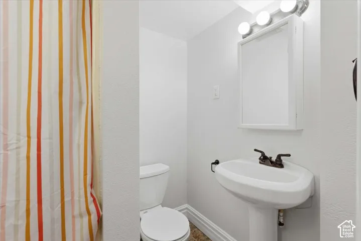 Basement Bath: Pedestal sink with dark bronze-finish fixtures, wall-mounted mirrored medicine cabinet, and three-bulb vanity lighting