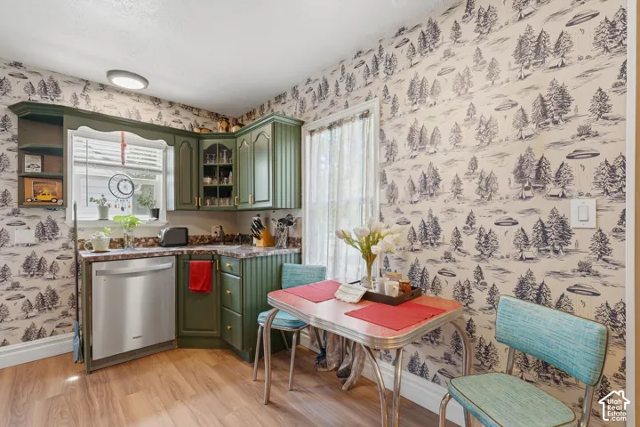 Corner kitchen featuring green cabinetry, wood-finish flooring, a stainless steel dishwasher, and a window