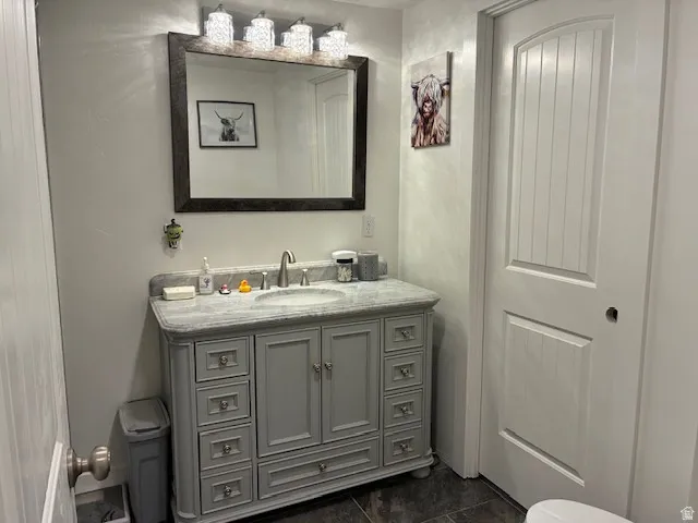 Vanity with a light gray finish, undermount sink, and stone-finish countertop