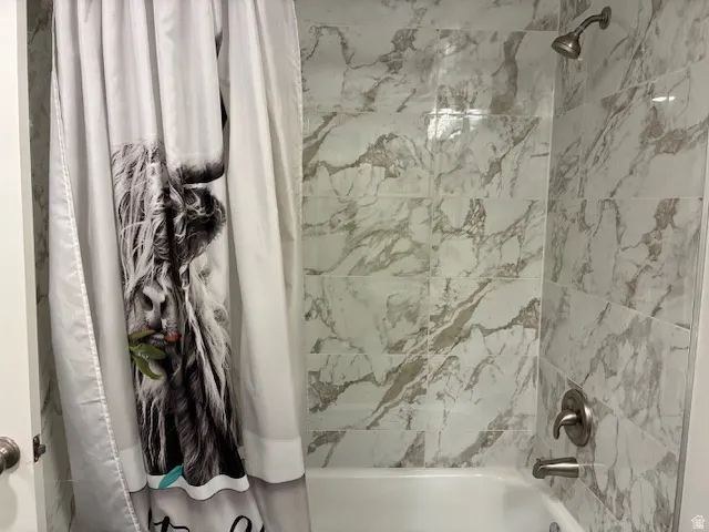 Bathtub and shower combination with tile surround, brushed nickel fixtures, and a curved shower arm