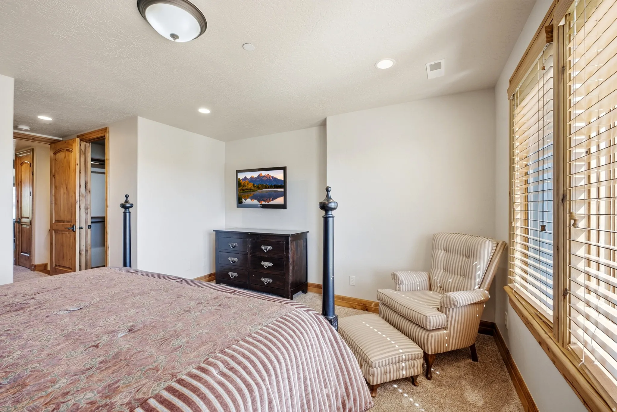 Carpeted room featuring wood-finish window frames, recessed lighting, and a built-in closet with bi-fold wood doors