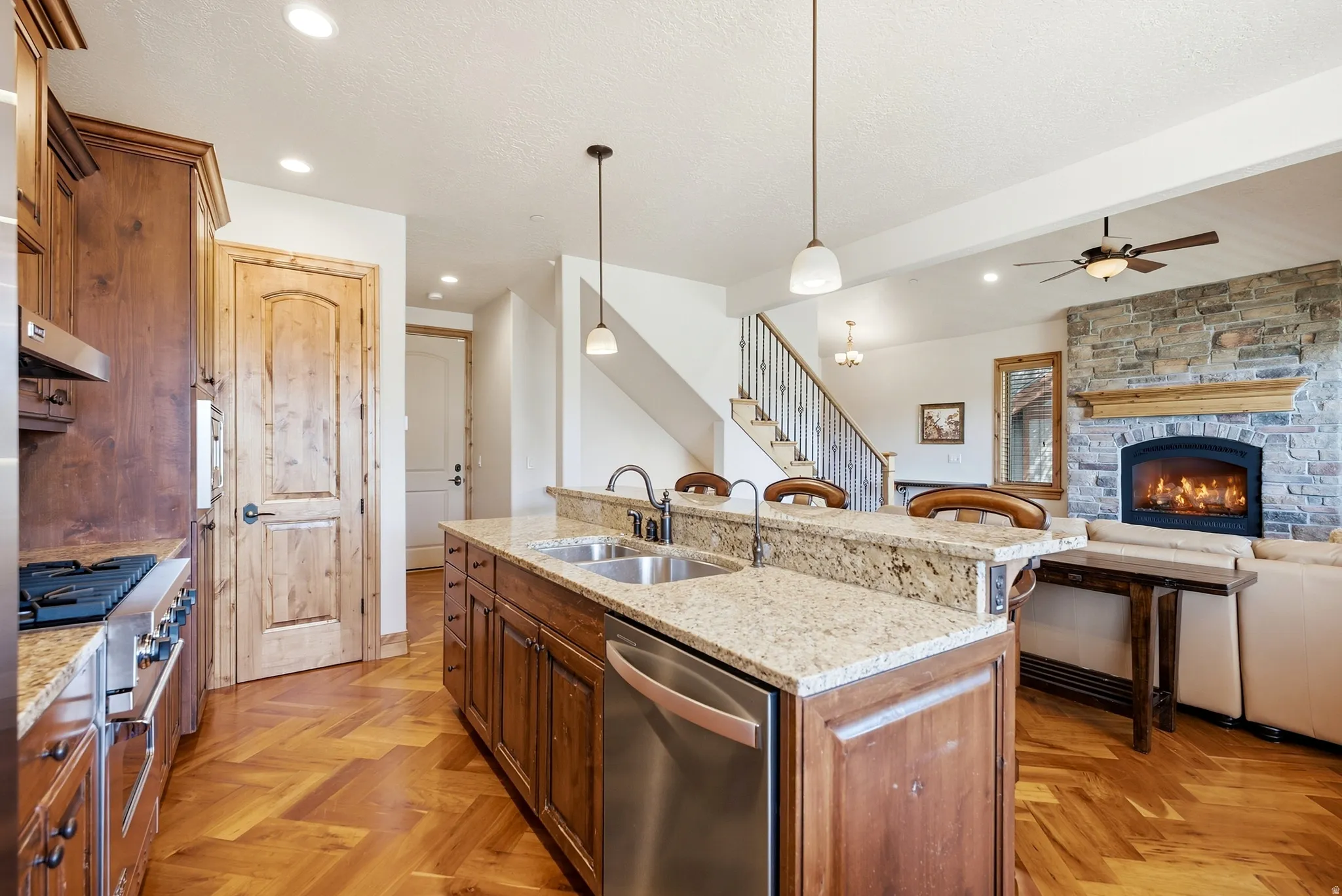 Wood-finish flooring, stone fireplace, stainless steel appliances, wood cabinetry, and granite countertops
