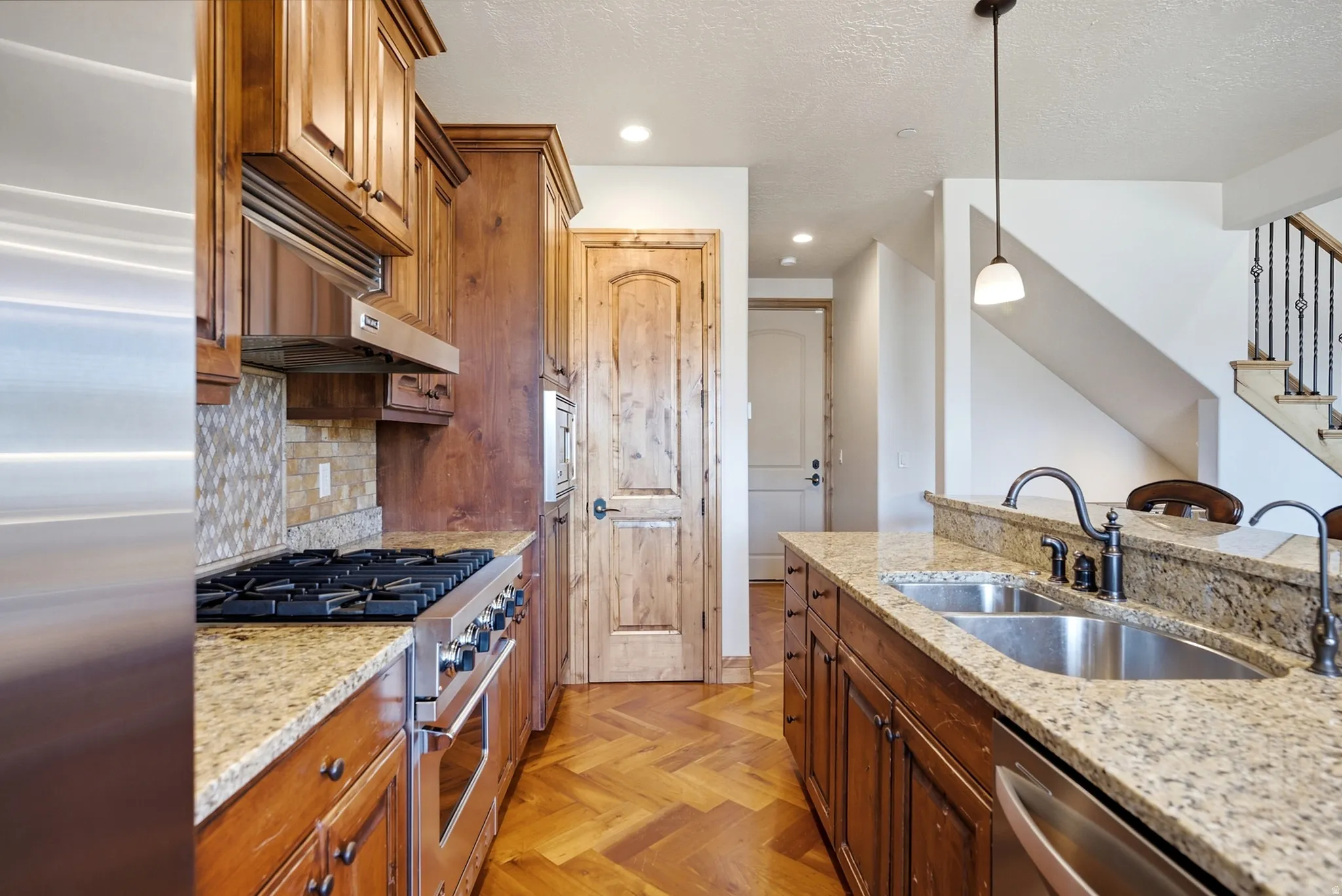 Kitchen featuring a gas range, stainless steel appliances, granite countertops, and wood-finish flooring