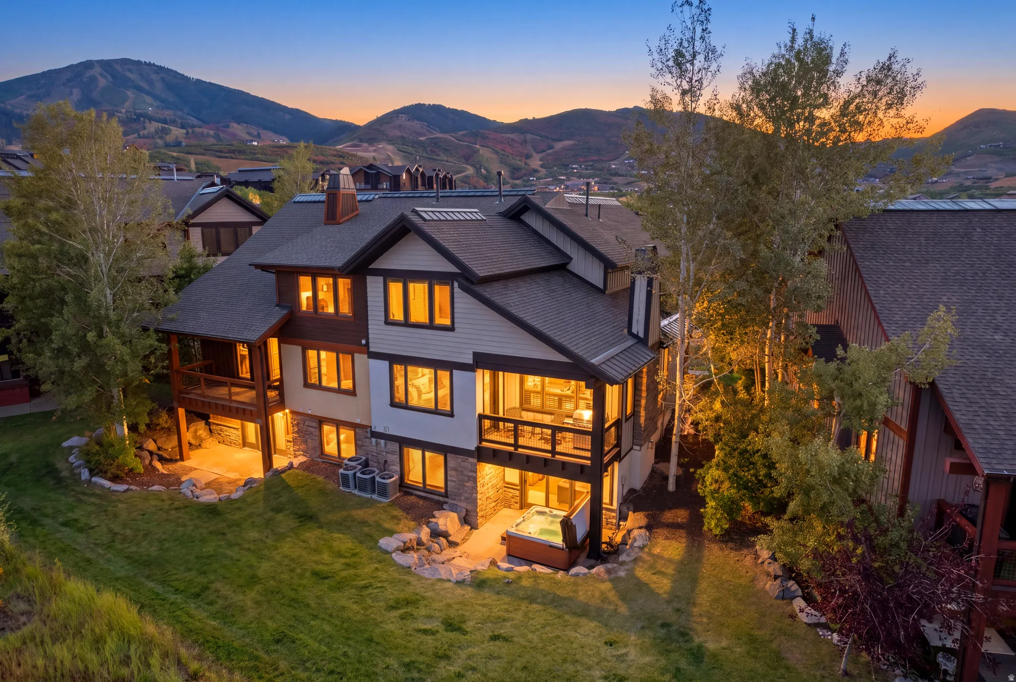 Multi-level exterior featuring stone and siding, multiple balconies, an outdoor patio, and an integrated spa