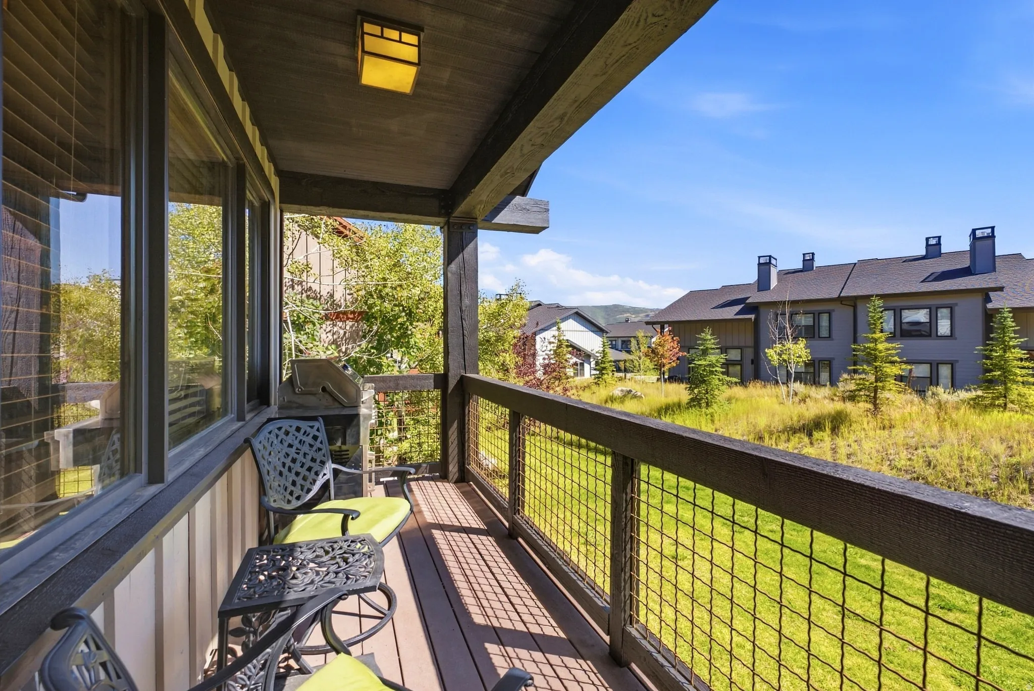 Covered balcony featuring wood-finish decking, dark-stained wood posts, and a wire mesh railing