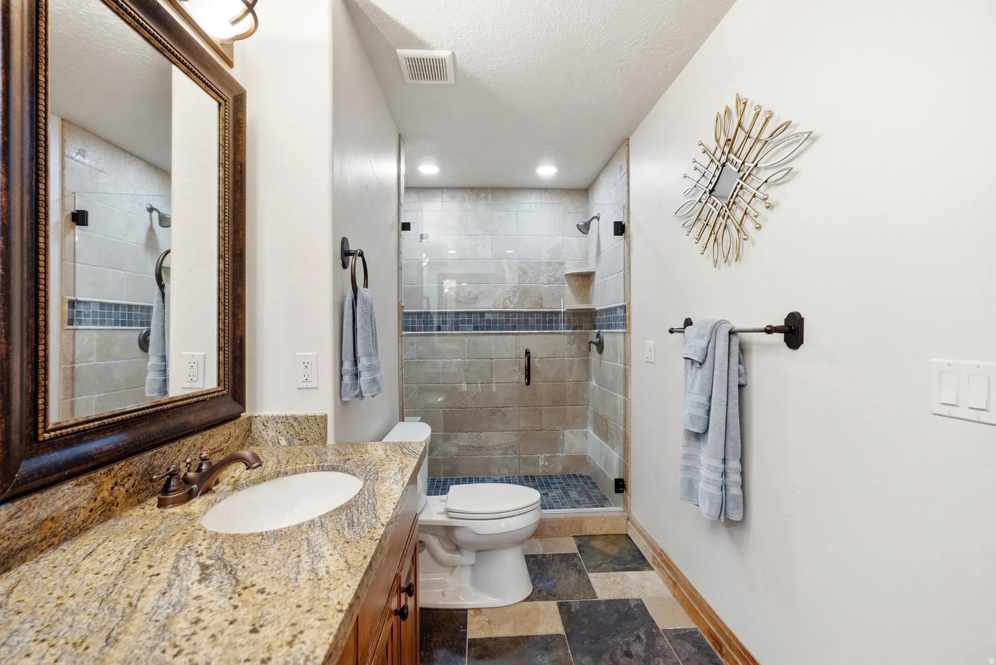 Vanity with stone countertop, undermount sink, and bronze-finish fixtures