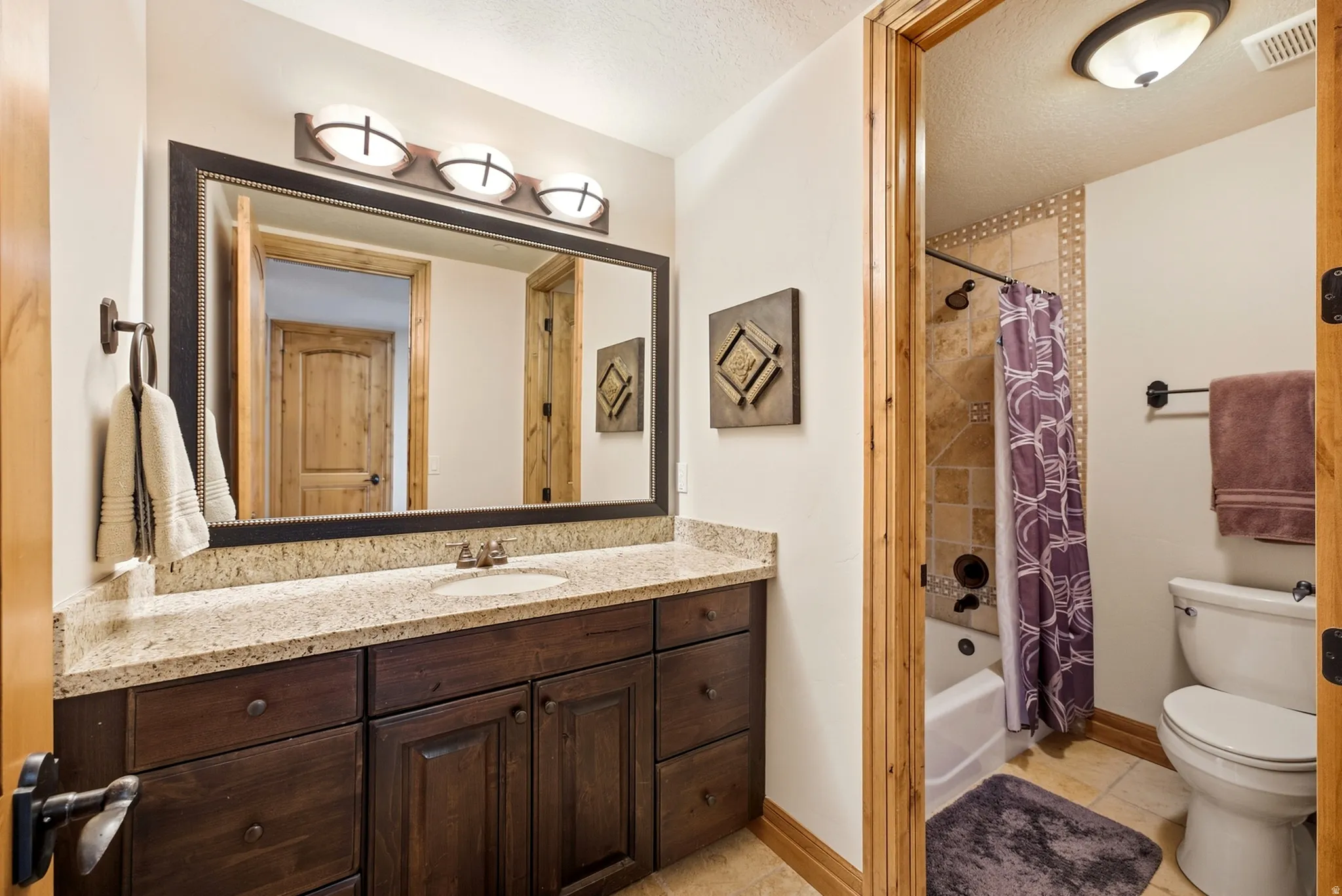 Warm bathroom featuring a wood vanity with granite countertop and a large framed mirror