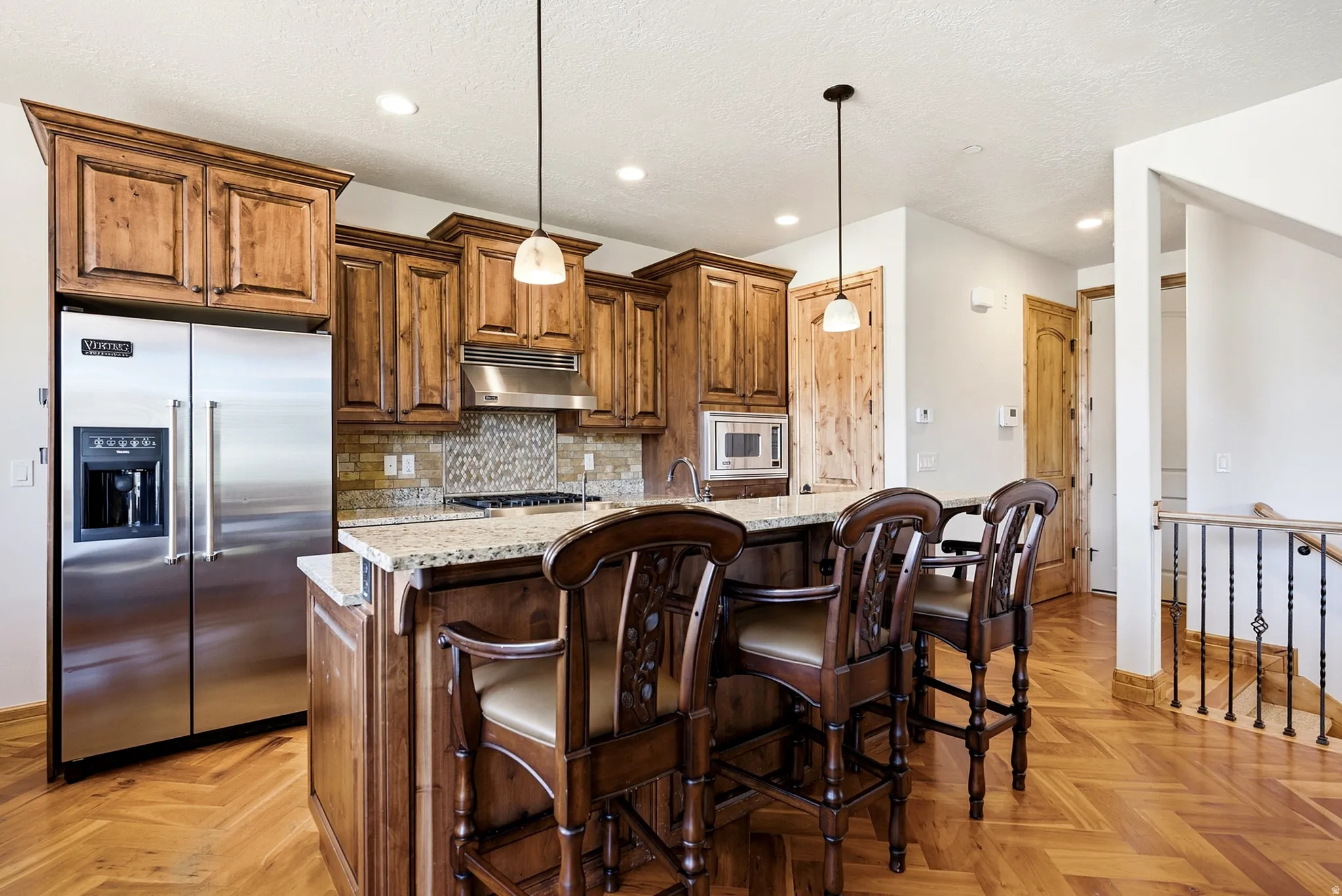 Kitchen featuring wood cabinetry, stainless steel appliances, a stone countertop island, and a decorative tile backsplash