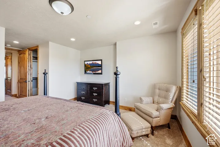 Carpeted room featuring wood-finish window frames, recessed lighting, and a built-in closet with bi-fold wood doors