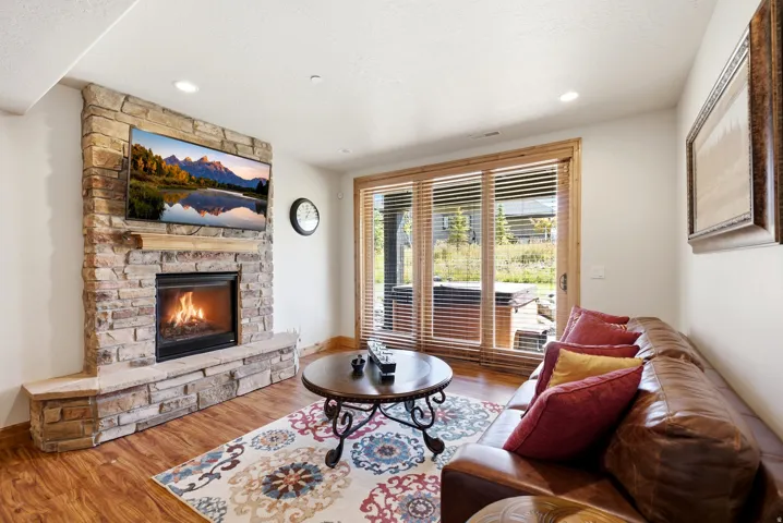 Stone-clad fireplace with hearth, wood-finish flooring, recessed lighting, and wooden-framed glass sliding doors