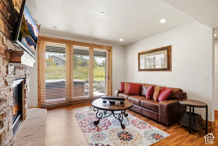 Stacked stone fireplace with mantel, hardwood-finish flooring, recessed lighting, and expansive glass sliding doors