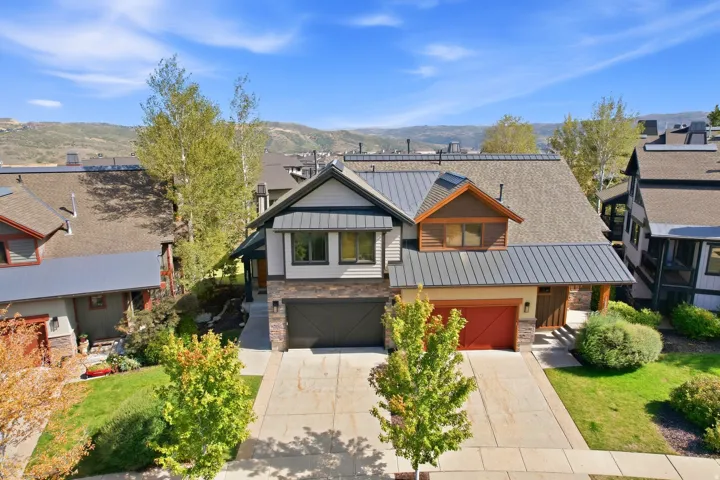 Contemporary exterior featuring mixed material siding, dual garages, and a metal roof accent