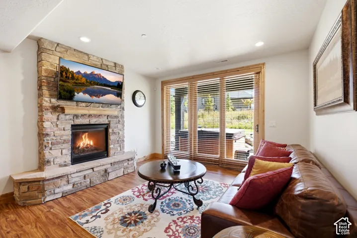 Stone-clad fireplace with hearth, wood-finish flooring, recessed lighting, and wooden-framed glass sliding doors