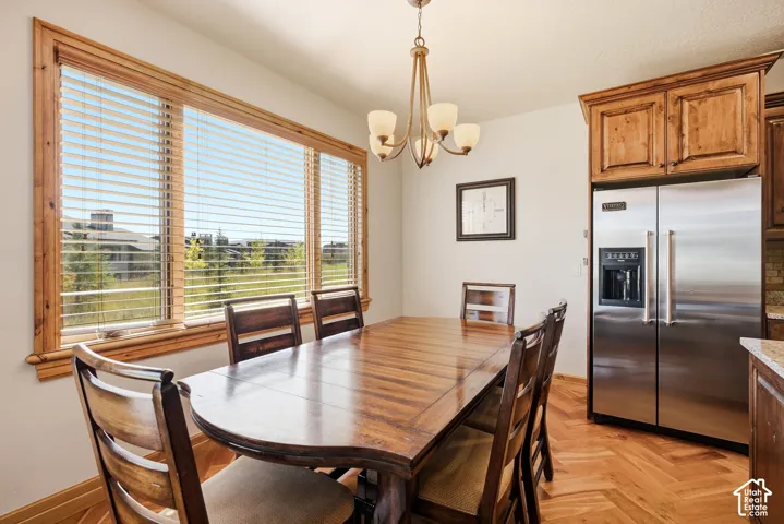 Spacious dining area featuring a large window with wood trim, wood-finish flooring, and a contemporary chandelier