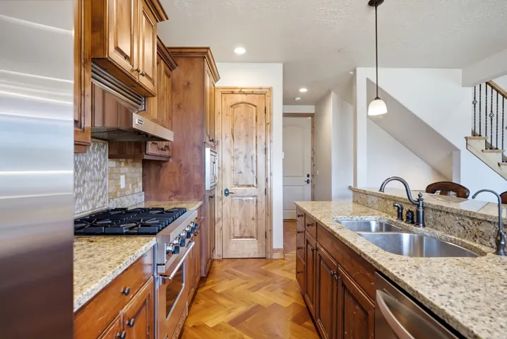 Kitchen featuring a gas range, stainless steel appliances, granite countertops, and wood-finish flooring