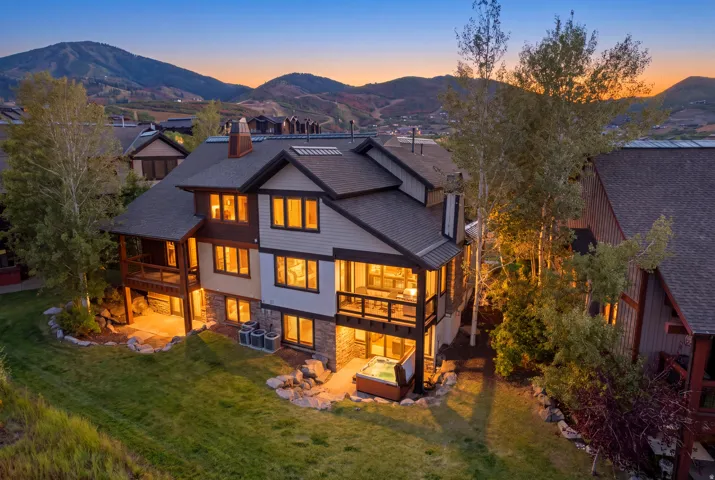 Multi-level exterior featuring stone and siding, multiple balconies, an outdoor patio, and an integrated spa