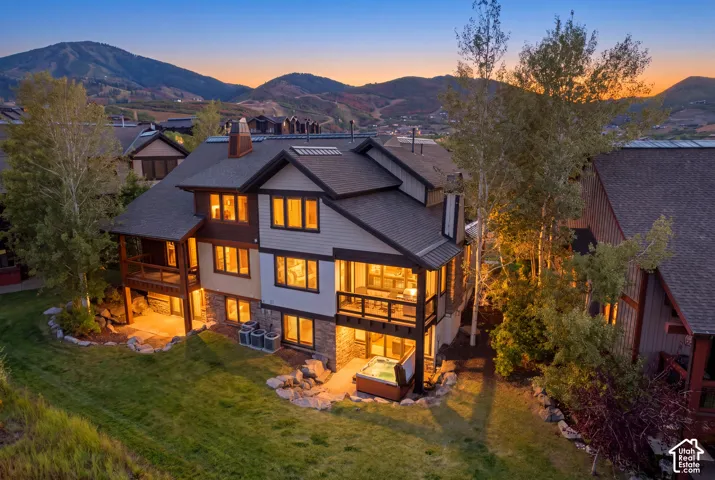 Multi-level exterior featuring stone and siding, multiple balconies, an outdoor patio, and an integrated spa