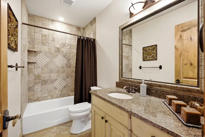 Stone-look tile shower surround with decorative accents and built-in shelving