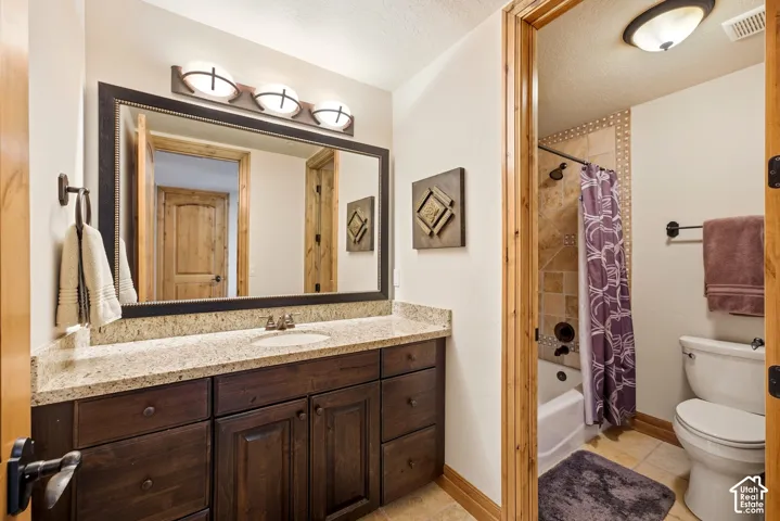 Warm bathroom featuring a wood vanity with granite countertop and a large framed mirror