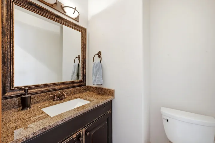 Vanity with a granite-style countertop, undermount sink, and dark wood-finish cabinetry