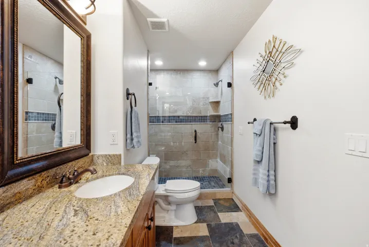 Vanity with stone countertop, undermount sink, and bronze-finish fixtures