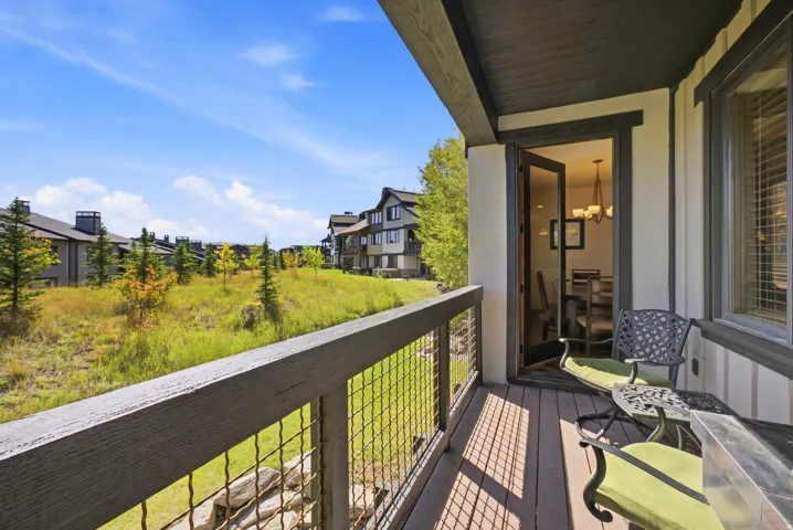 Outdoor balcony featuring wood-finish decking, dark wood railings with wire mesh infill, and a glass-paneled door