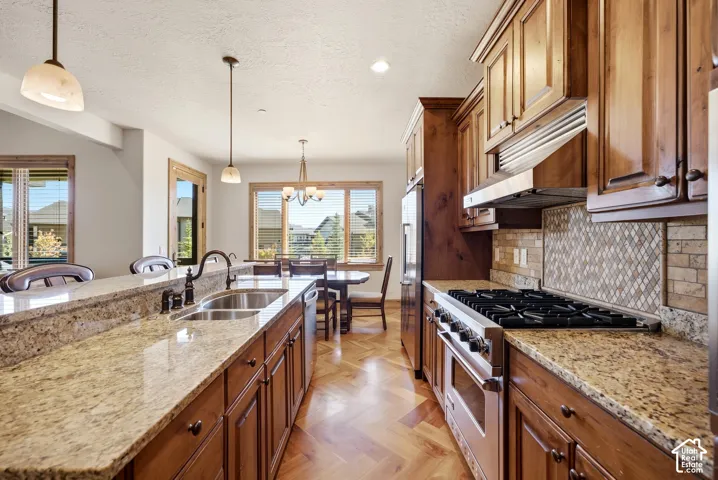 Gourmet kitchen with granite countertops, hardwood cabinetry, stainless steel appliances, and a herringbone wood-finish floor