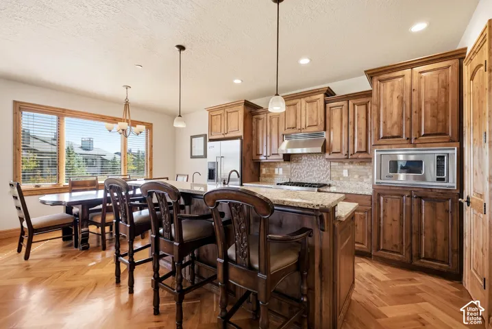 Kitchen featuring wood-finish flooring, granite countertops, wood cabinetry, a built-in stainless steel microwave, and pendant lighting