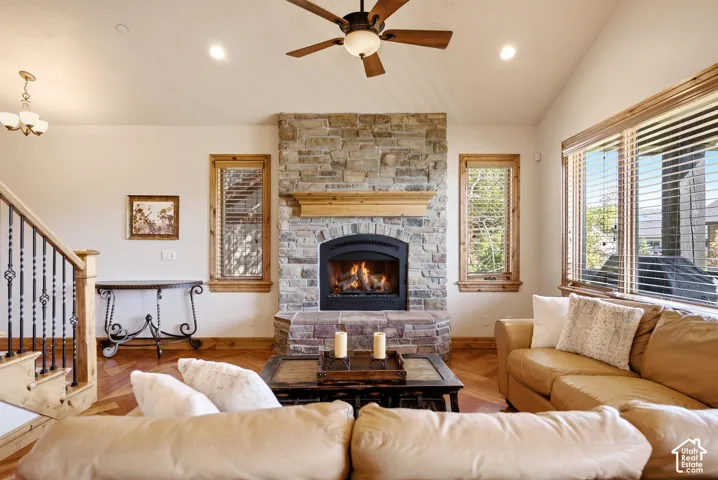 Stone-clad fireplace with a wood mantel, wood-finish flooring, and vaulted ceiling