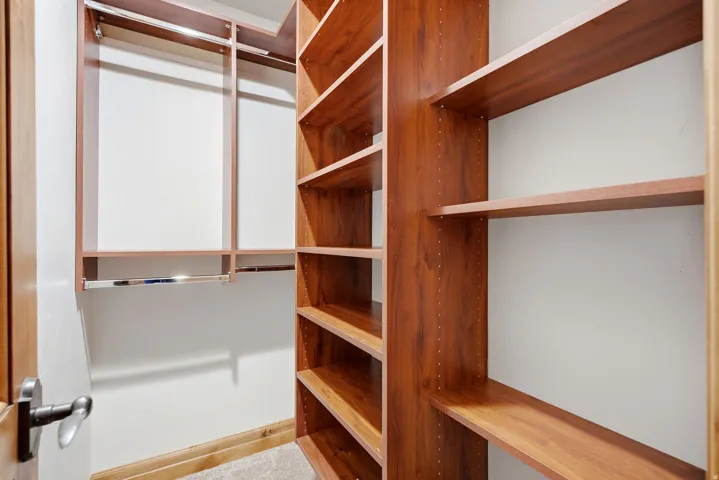 Custom closet system featuring wood-finish shelving and chrome hanging rods
