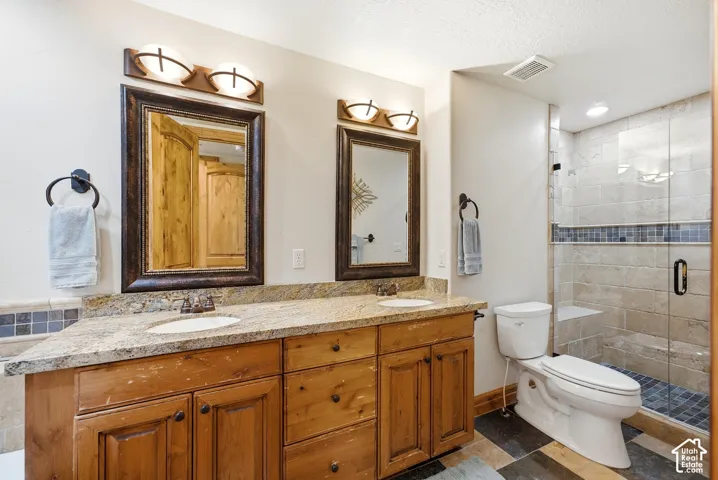 Dual vanity with granite countertop, wood-finish cabinetry, and individual framed mirrors