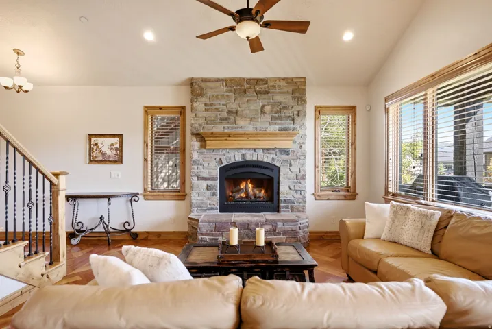 Stone-clad fireplace with a wood mantel, wood-finish flooring, and vaulted ceiling