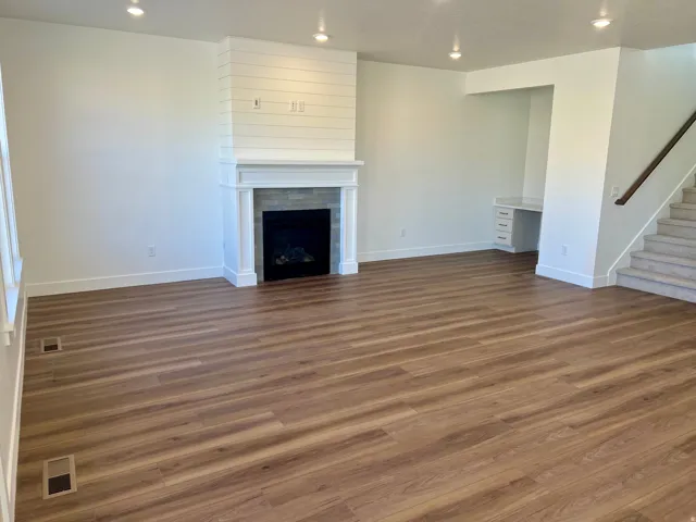 Wood-finish flooring, recessed lighting, and a fireplace with a shiplap accent wall