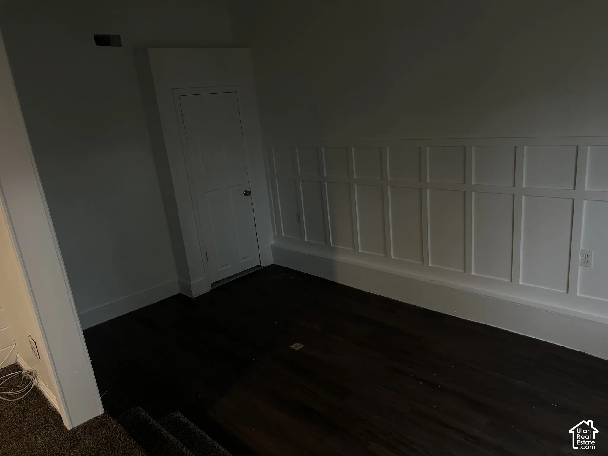 Dark wood-finish flooring, white paneled wall detailing, built-in storage, and white trim