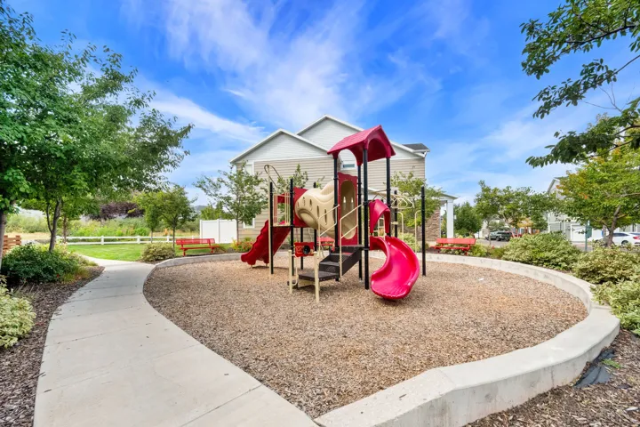 Outdoor recreation area featuring a multi-component play structure, wood chip ground cover, and a curved concrete border