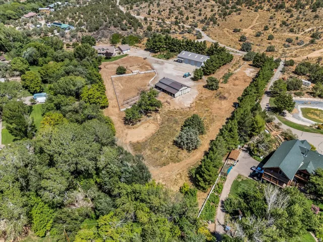 Expansive property featuring multiple outbuildings, fenced enclosures, and mature trees throughout