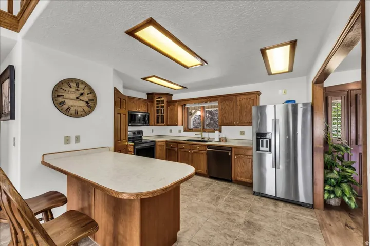 Kitchen featuring wood cabinetry, stainless steel appliances, a breakfast bar, and recessed lighting