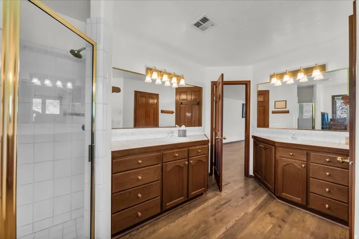 Bathroom with wood-finish flooring and dual vanity areas