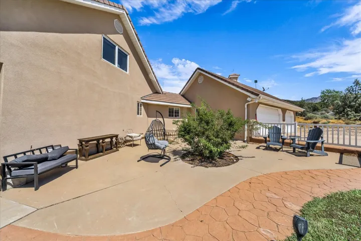 Expansive outdoor patio with concrete and textured paving, stucco exterior, and attached garage