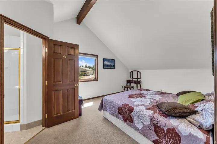 Vaulted ceilings with exposed wood beams, wood-trimmed window, and solid wood paneled door